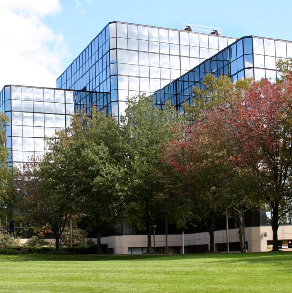 Glass commercial buildings surrounded by trees and greenery